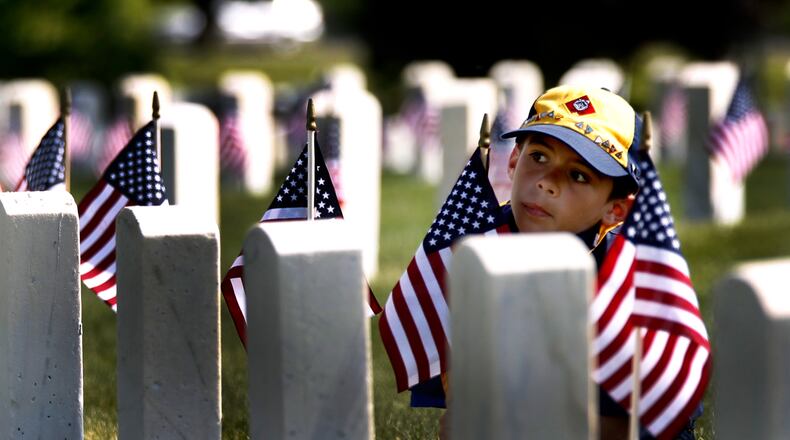 Cub Scout Jacob Terpenning, 8, a member of Beavercreek Pack 234, plants a flag during the Dayton National Cemetery Memorial Day grave decorating ceremony Saturday. Hundreds of Boy Scouts and Girl Scouts from the area placed 50,000 American flags on graves. The annual event was organized by the American Legion of Ohio and the Dayton National Cemetery. LISA POWELL / STAFF