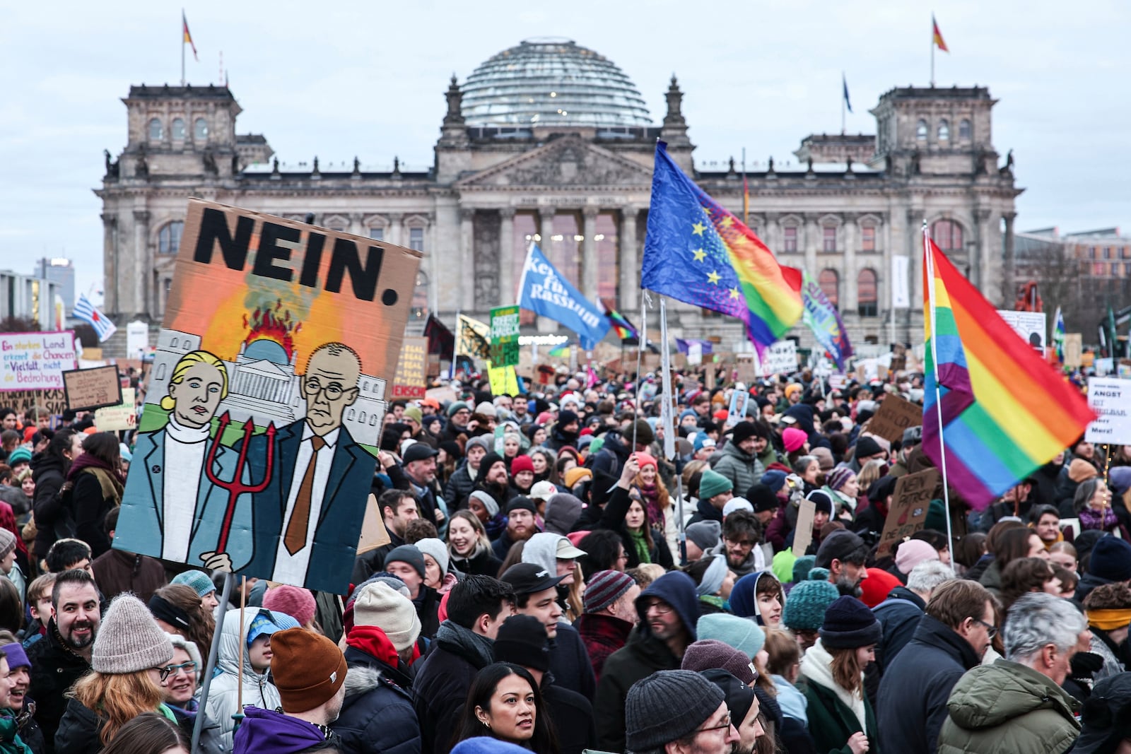 FILE - A protester holds a sign with a painted picture of Alice Weidel (AfD) and Friedrich Merz (CDU) with a burning Reichstag building and the inscription "No" during a demonstration in front of the Reichstag building in Berlin, Feb. 2, 2025. (Hannes P. Albert/dpa via AP)