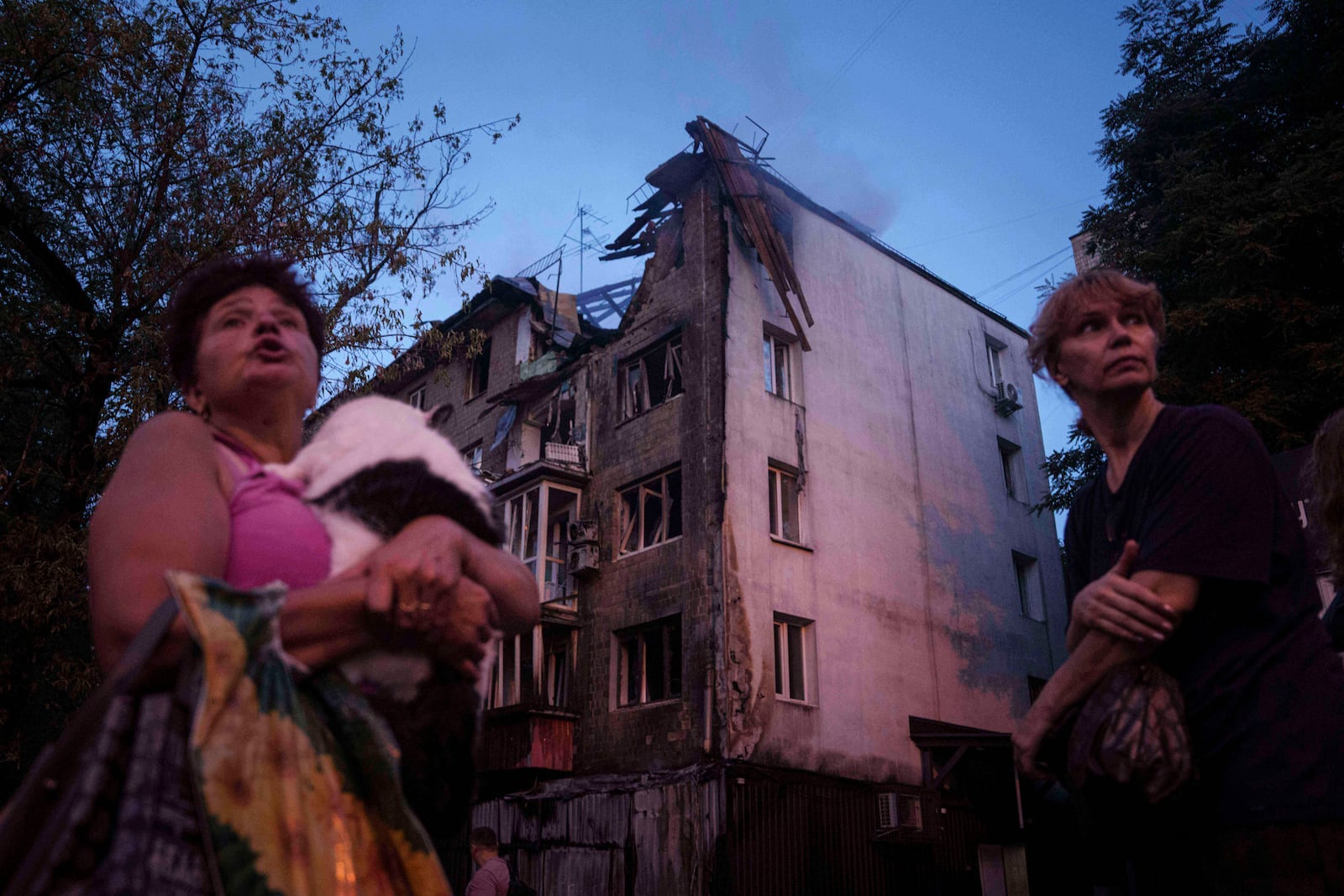 Local residents stand outside of their house which was heavily damaged by a Russian strike in Kyiv, Ukraine, on Thursday, July 10, 2025. (AP Photo/Evgeniy Maloletka)