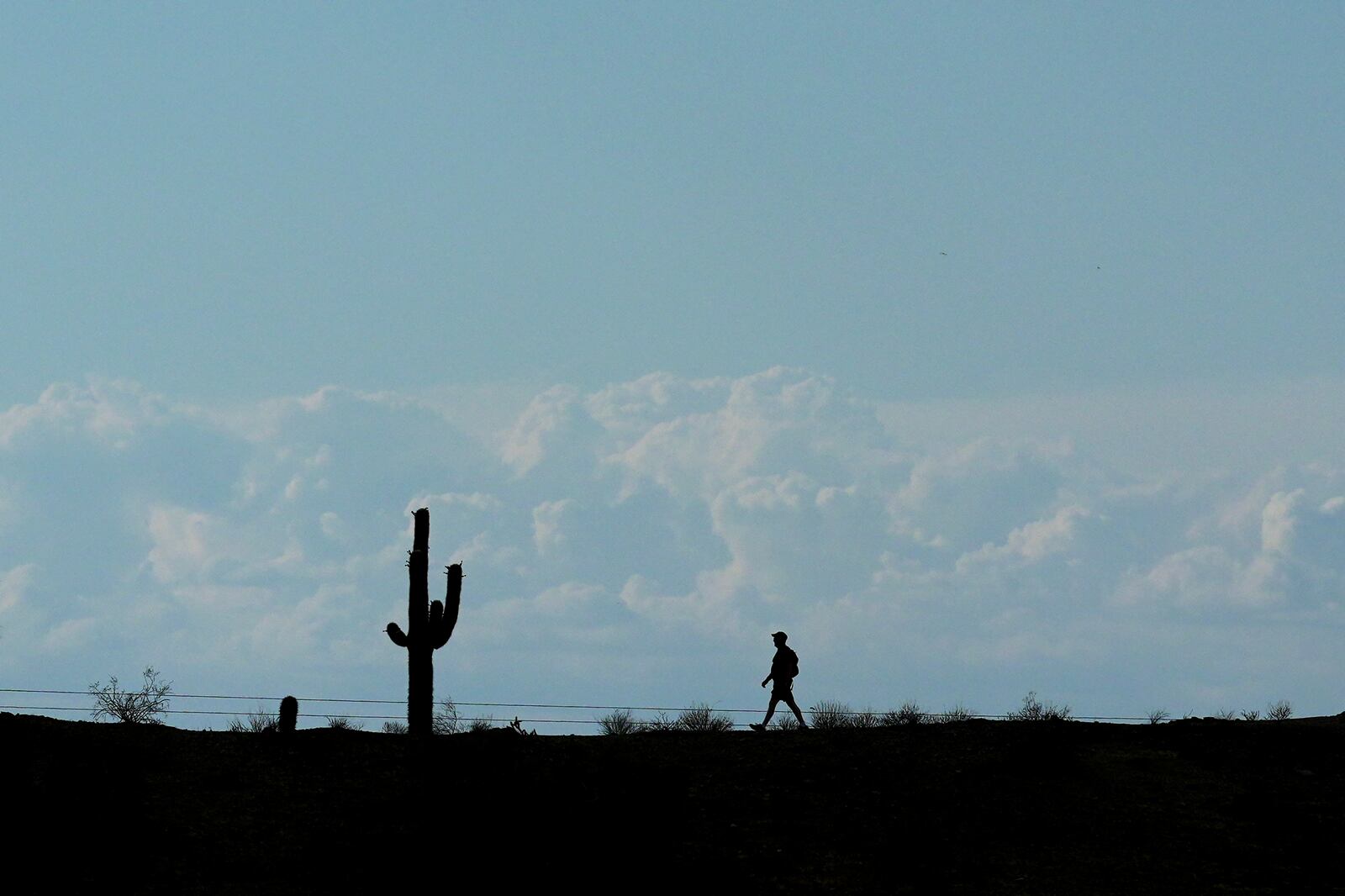 Storm clouds form in the distance as a hiker walks along a path in South Mountain Park Wednesday, June 4, 2025, in Phoenix. (AP Photo/Ross D. Franklin)