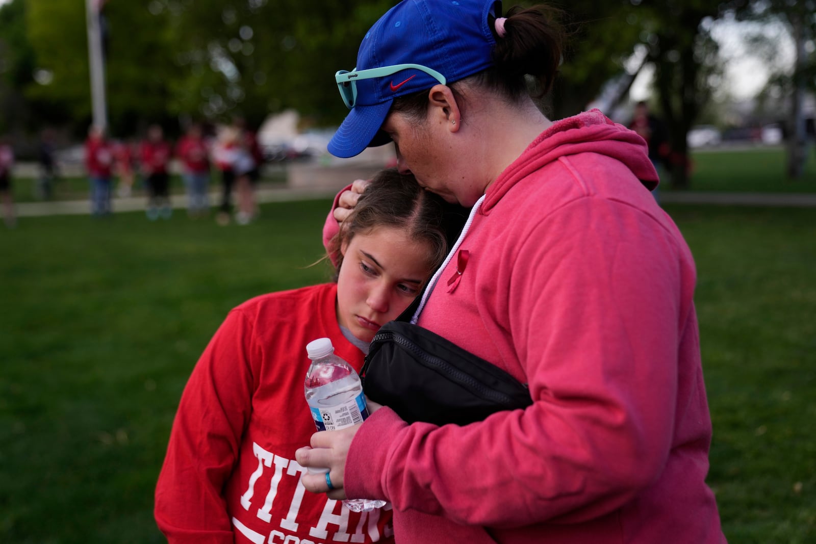 Heather Glessner comforts her 9-year-old daugher Coralie at a vigil for three young children and a teenager who were killed when a car barreled through a building used for an after-school camp, Tuesday, April 29, 2025, in Chatham, Ill. (AP Photo/Erin Hooley)