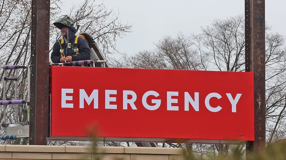 A man in a lift works on the new sign in front of the Kettering Health medical center at the intersection of Home Road and North Limestone Street Tuesday, March 22, 2022. The medical center is located in the old Kroger location. BILL LACKEY/STAFF