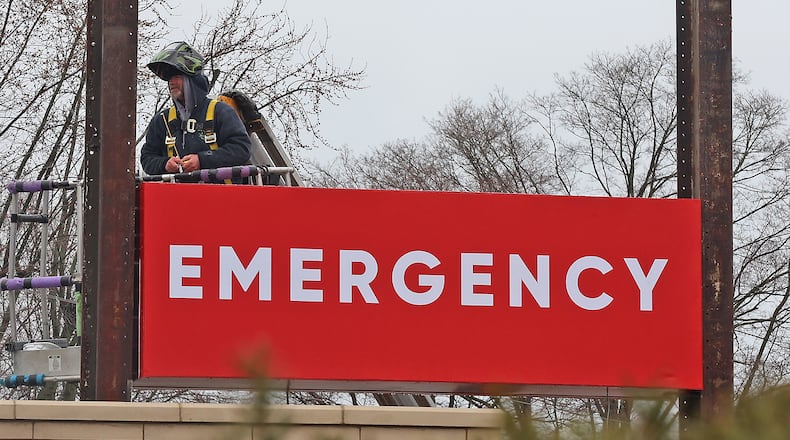 A man in a lift works on the new sign in front of the Kettering Health medical center at the intersection of Home Road and North Limestone Street Tuesday, March 22, 2022. The medical center is located in the old Kroger location. BILL LACKEY/STAFF