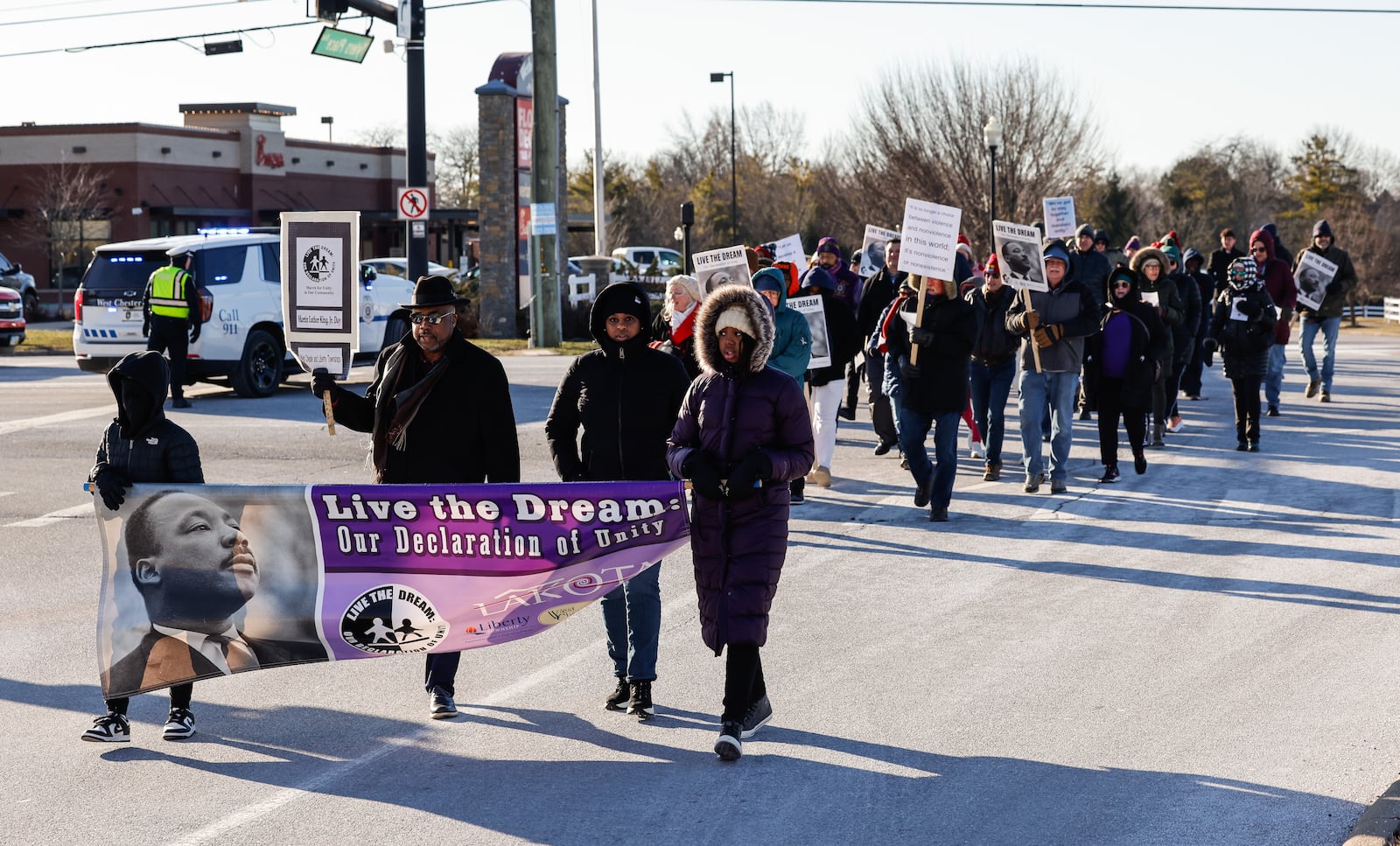 A group braves the bitter cold to march during the Martin Luther King Jr. Day celebration Monday morning, Jan. 19, 2026 on Tylers Place Blvd. on the West Chester Township and Liberty Township border. NICK GRAHAM/STAFF