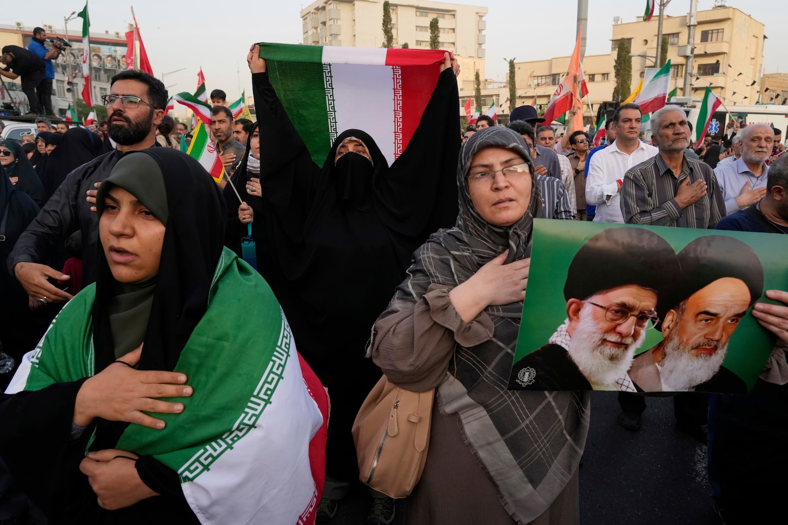 Iranian protesters hold their country's flags and a poster of Supreme Leader Ayatollah Ali Khamenei, left, and the late revolutionary founder Ayatollah Khomeini in an anti-U.S. and anti-Israeli rally at Enqelab-e-Eslami (Islamic Revolution) square in downtown Tehran, Iran, Tuesday, June 24, 2025. (AP Photo/Vahid Salemi)