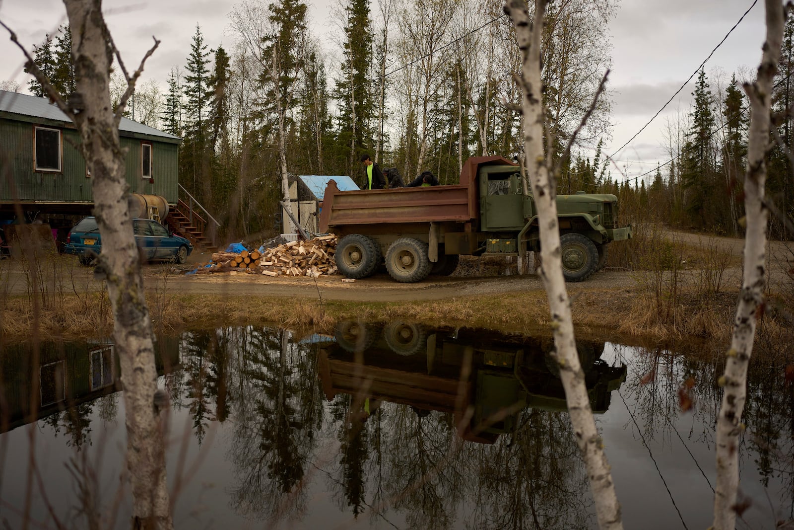 Nathan Moses, from left, Morris Demoski and Marissa McCarty deliver wood to an elder Monday, May 19, 2025, in Galena, Alaska. (AP Photo/John Locher)