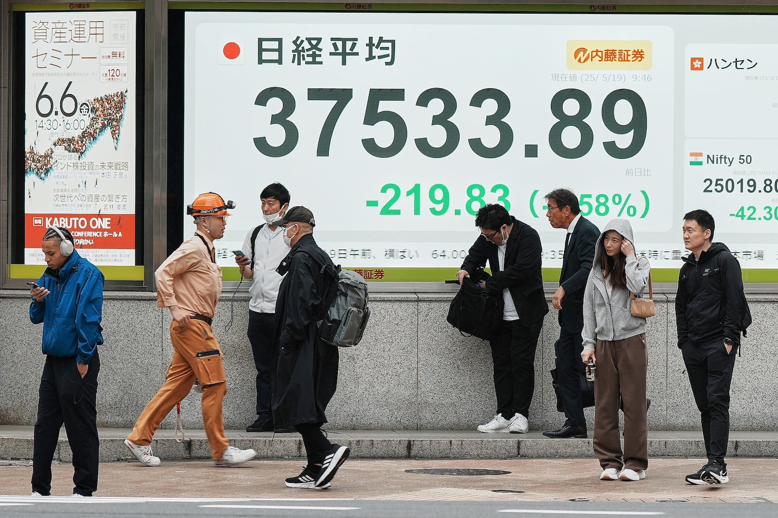 People stand in front of an electronic stock board showing Japan's Nikkei index at a securities firm Monday, May 19, 2025, in Tokyo. (AP Photo/Eugene Hoshiko)