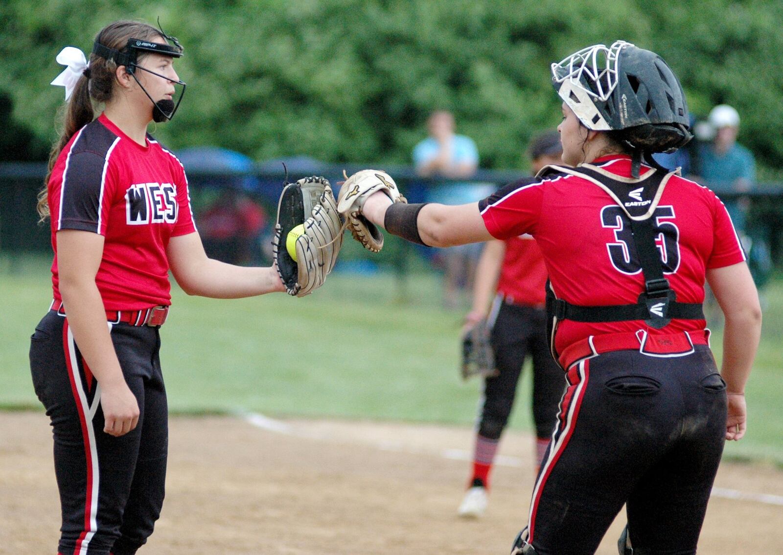 Lakota West pitcher K.K. Mathis and catcher Kendall Forren meet in the circle Wednesday during a 2-0 win over Harrison in a Division I regional softball semifinal at Centerville. RICK CASSANO/STAFF