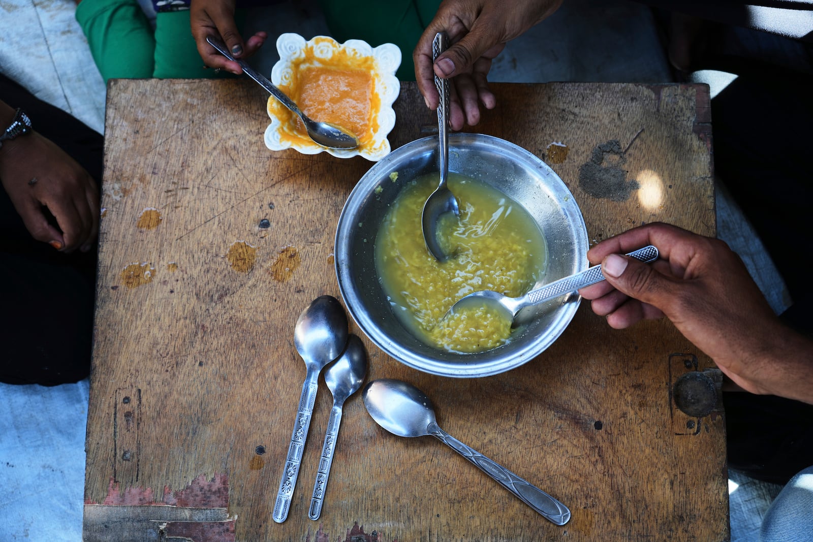 The Al-Arja family eats lentil soup inside their tent at a camp for displaces Palestinians in the Muwasi, Khan Younis, Gaza, Wednesday, May 21, 2025. (AP Photo/Abdel Kareem Hana)
