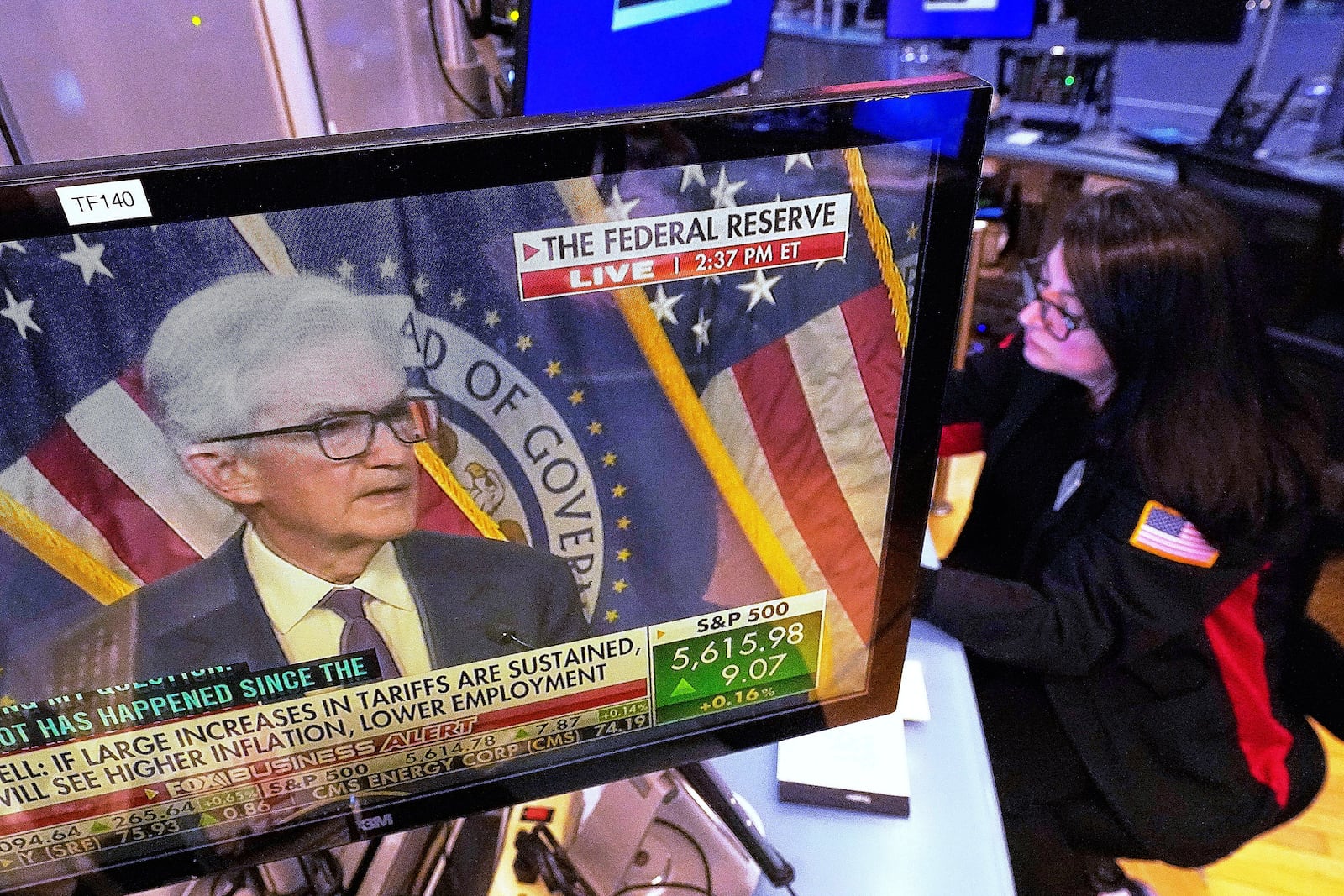 The news conference of Federal Reserve Chair Jerome Powell is displayed on a screen in the booth of trader Phyllis Arena Woods, on the floor of the New York Stock Exchange, Wednesday, May 7, 2025. (AP Photo/Richard Drew)