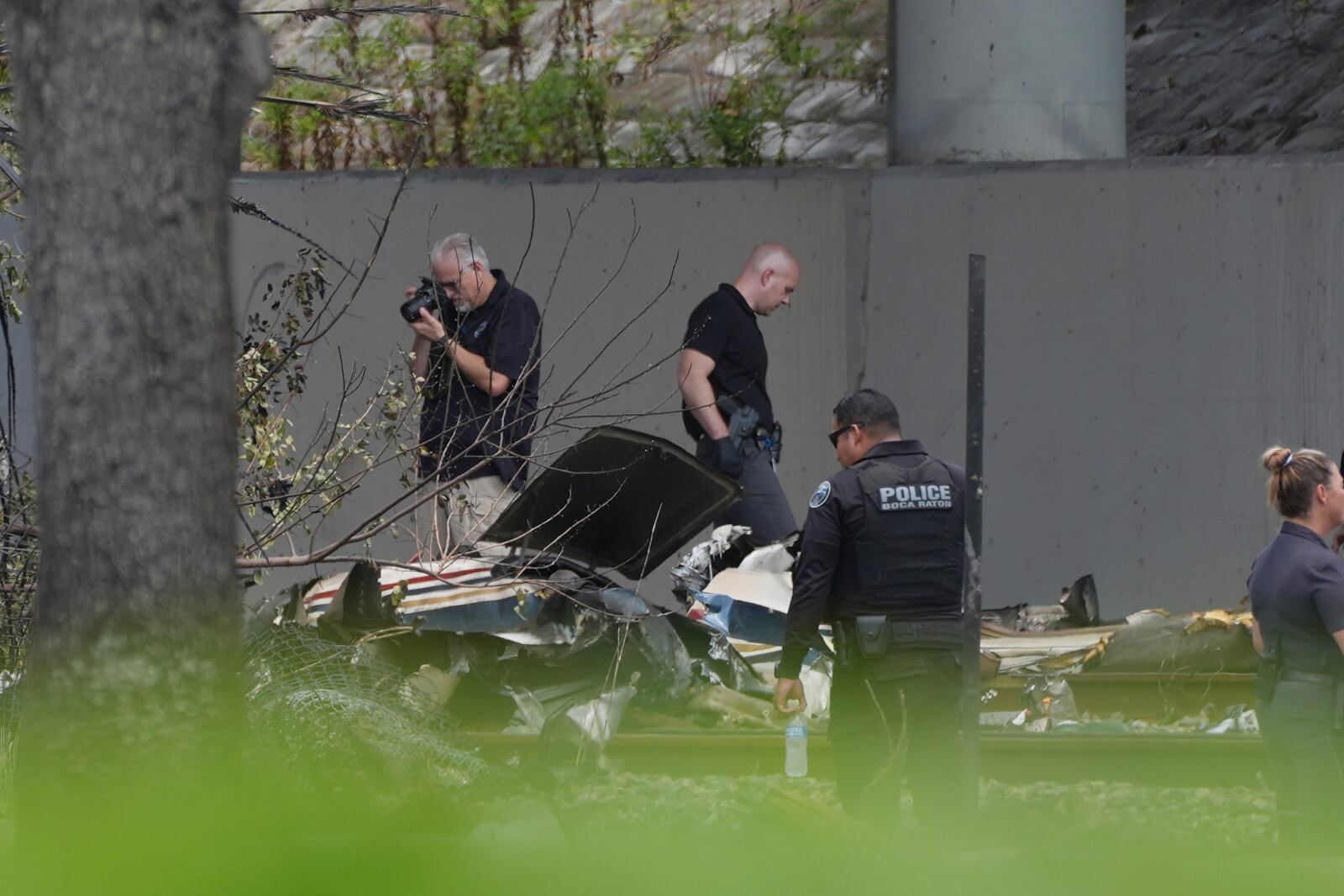 Emergency personnel respond to the area where a small plane crashed on the railroad tracks beneath the overpass near Interstate 95 in Boca Raton, Fla., on Friday, April 11, 2025. (AP Photo/Marta Lavandier)