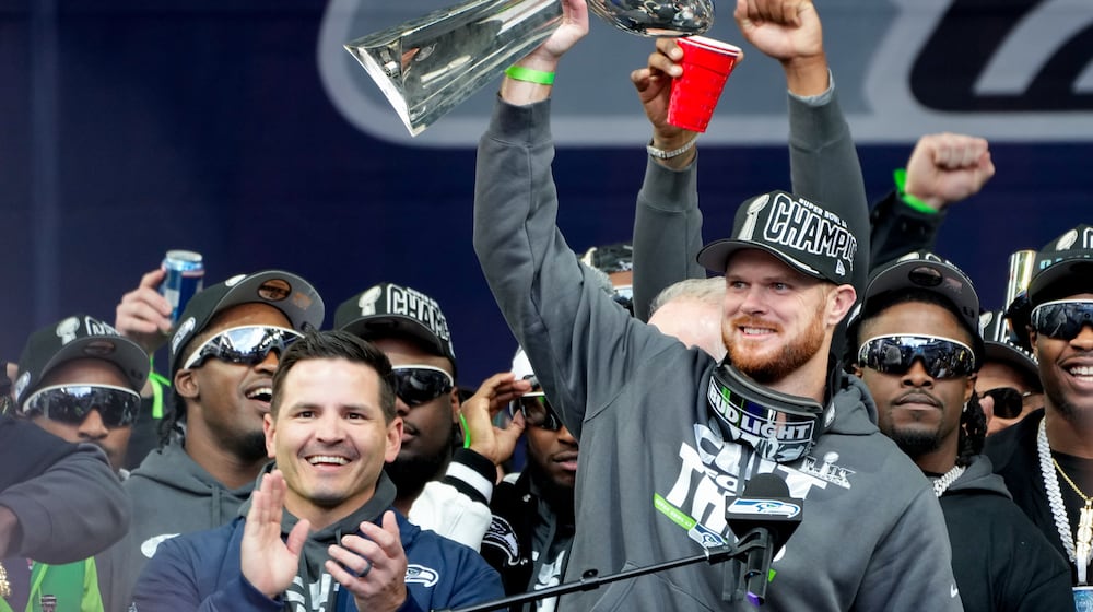 Seattle Seahawks quarterback Sam Darnold holds the Lombardi Trophy as head coach Mike MacDonald celebrates at left during the team's NFL football Super Bowl 60 celebration at Lumen Field, Wednesday, Feb. 11, 2026, in Seattle. (AP Photo/Stephen Brashear)