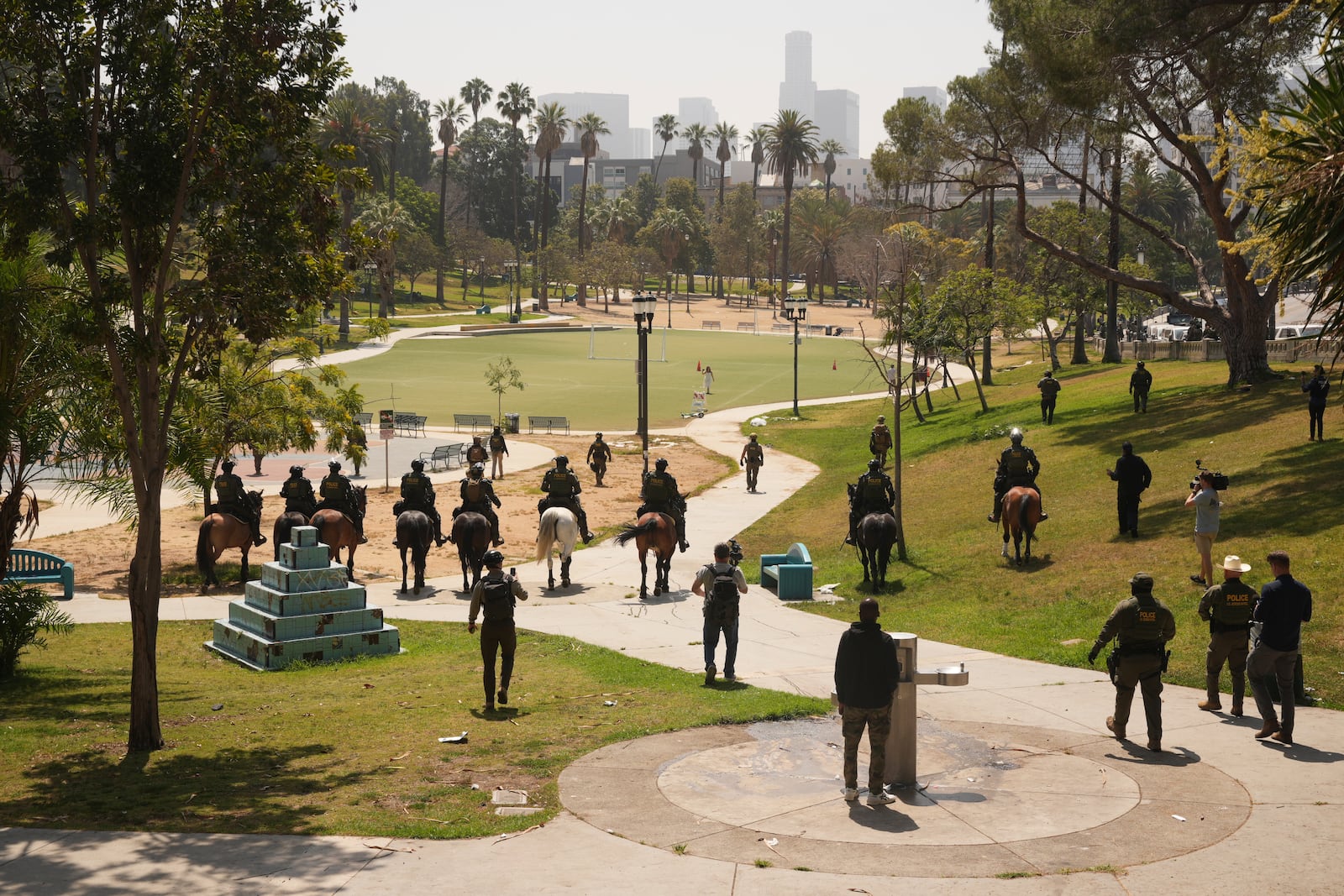 Federal agents ride on horseback at MacArthur Park Monday, July 7, 2025, in Los Angeles. (AP Photo/Damian Dovarganes)