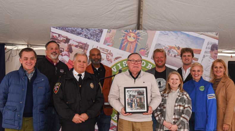 The City of Urbana was named Best Hometown by Ohio Magazine. To celebrate this achievement, the Champaign County Chamber of Commerce & Visitors Bureau held a special ceremony on Second Saturday, Nov. 9, in downtown Urbana. Front row, from left to right: Editor of Ohio Magazine Jim Vickers, police Chief Matt Lingrell, Mayor Bill Bean, Chamber Director Sara Neer, Visitors Representative Polly Trenor, Director of GrandWorks Stacy Weller. Back row, left to right: Urbana City School Superintendent Charles Thiel, Kalen Howell Sr. Jamon Sellman and Justin Weller. Contributed/Tammi Feehan for Urbana Tomorrow.