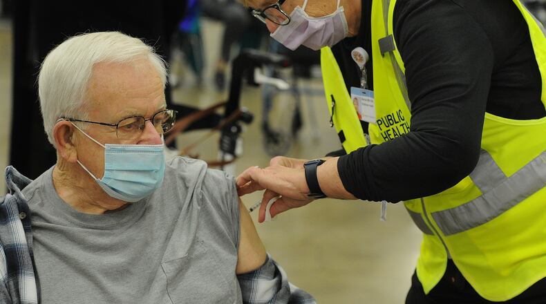 Michael Whitesell, 81, of Englewood, receives his COVID-19 vaccination from a healthcare worker Wednesday morning, Jan. 20, 2021 at the Dayton Convention Center. MARSHALL GORBY\STAFF