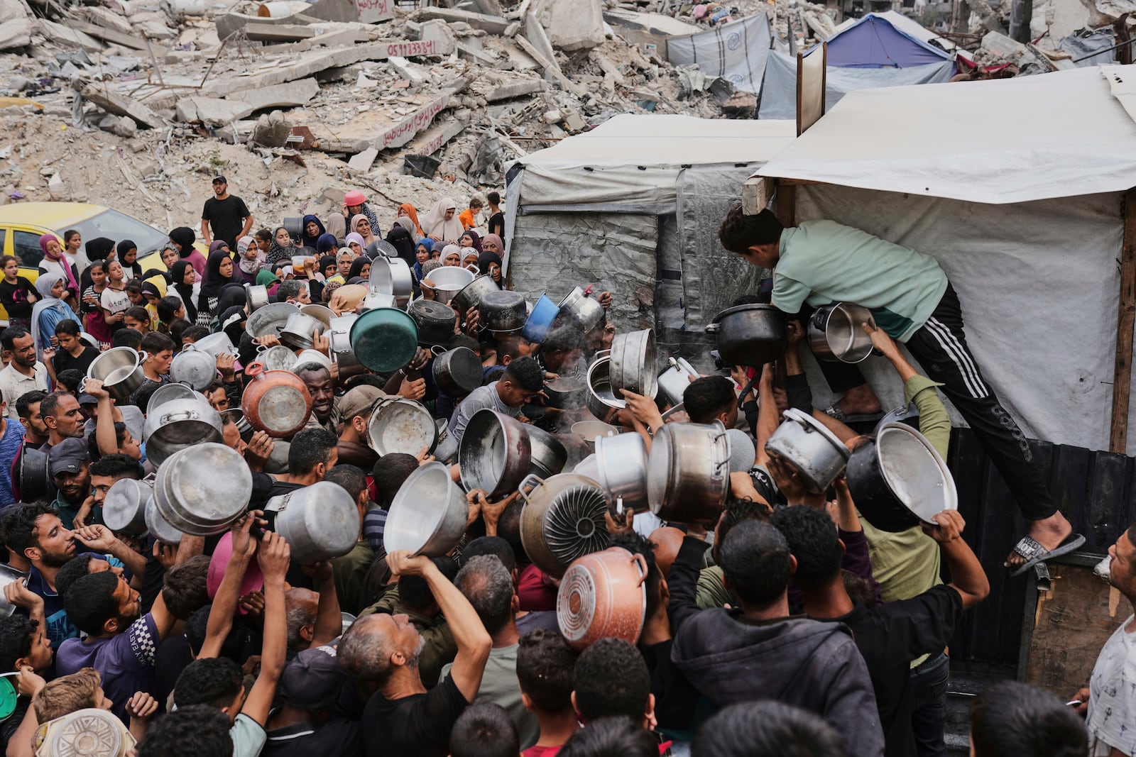 Palestinians struggle to get donated food at a community kitchen in Jabalia, northern Gaza Strip, Thursday, May 15, 2025. (AP Photo/Jehad Alshrafi)