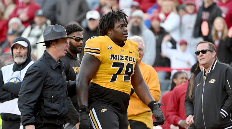 Missouri offensive lineman Armand Membou (79) is escorted off the field after being ejected from the game during an NCAA college football game against Arkansas Friday, Nov. 24, 2023, in Fayetteville, Ark. (AP Photo/Michael Woods)