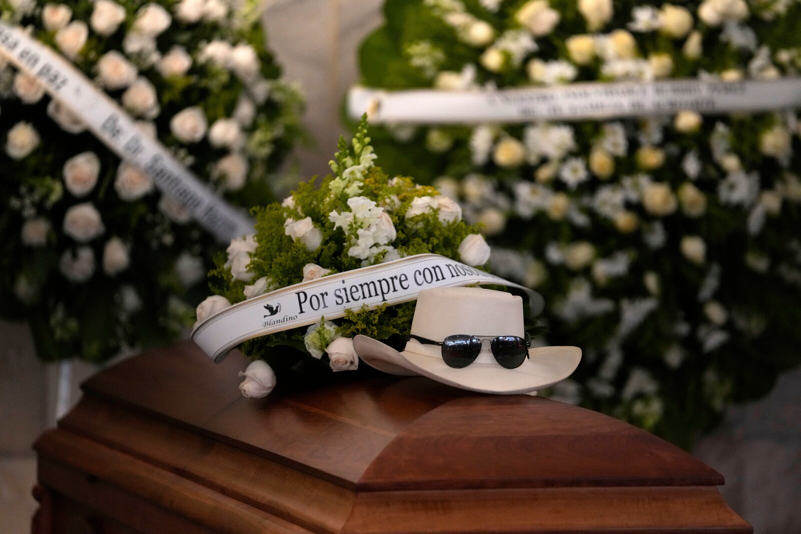 The hat and sunglasses of Dominican singer Rubby Perez, who died in the roof collapse at the Jet Set nightclub during his merengue concert, sit on his casket during his wake at the Domingo Brito National Theater in Santo Domingo, Dominican Republic, Thursday, April 10, 2025. (AP Photo/Matias Delacroix)