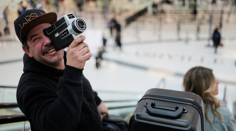 Jordan Heid uses an old film camera as he arrives for his flight at the Nashville International Airport, Tuesday, Nov. 25, 2025, in Nashville, Tenn. (AP Photo/George Walker IV)