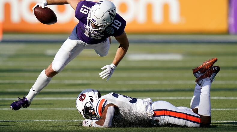 Northwestern wide receiver Riley Lees (19) tries to leap over Auburn defensive back Jaylin Simpson, lower right, after a short gain during the second half of the Citrus Bowl NCAA college football game, Friday, Jan. 1, 2021, in Orlando, Fla. Northwestern defeated Auburn 35-19. (AP Photo/John Raoux)