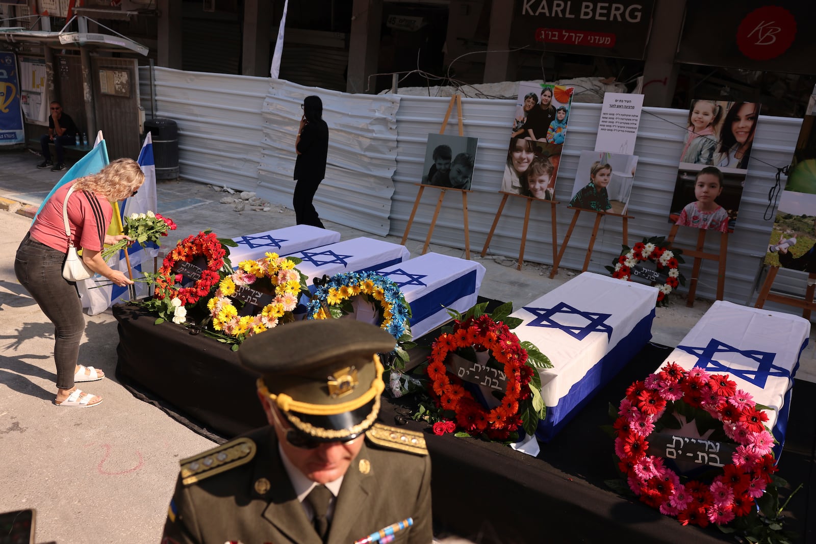 People attend a memorial service ceremony for five Ukrainian citizens who were killed in a Iranian missile strike as they stand next to a damaged residential building in Bat Yam, Israel, Monday, June 30, 2025. (AP Photo/Tomer Apelbaum)