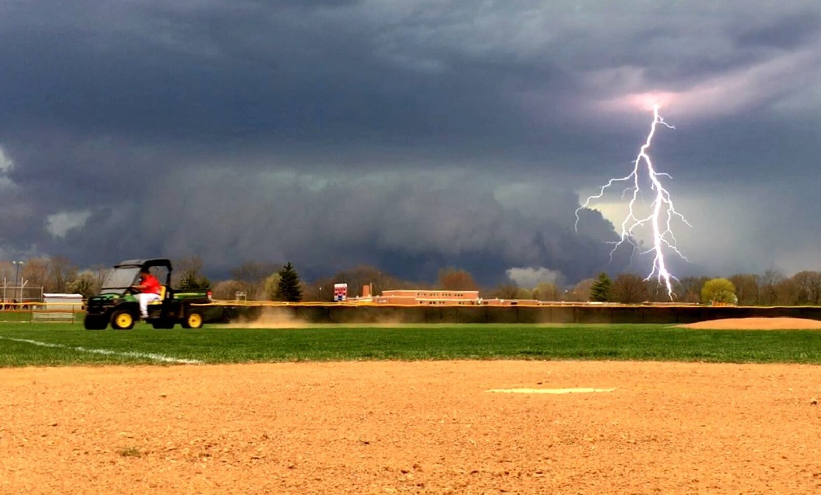 Carlisle coach Chris Hawkins works on Sam Franks Field after lightning suspended Wednesday’s game against visiting Madison in the bottom of the first inning. NICK GRAHAM/STAFF