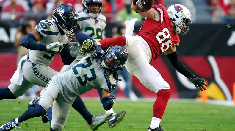 Seattle Seahawks cornerback Sidney Jones (23) upends Arizona Cardinals tight end Zach Ertz (86) as Seahawks outside linebacker Jordyn Brooks (56) and Seahawks cornerback Ugo Amadi (28) close in during the first half of an NFL football game Sunday, Jan. 9, 2022, in Glendale, Ariz. (AP Photo/Ralph Freso)