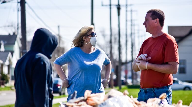 Hamilton City School workers Debbie Reed, middle, and Gary Schweinfest set up a table to distribute lunches Thursday, March 26 at the corner of East and Hensley Avenues in Hamilton. Hamilton City Schools is among many schools in the area supplying students with meals throughout the week since school is out due to the coronavirus pandemic. Starting Monday March 30 they will be distributing meals two days a week, Mondays and Wednesdays, at nearly 30 locations. Monday’s meal bag will include 2 breakfasts and 2 lunches and Wednesday’s bag will include 3 breakfasts and 3 lunches. NICK GRAHAM / STAFF