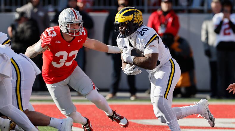 Michigan running back Kalel Mullings, right, runs the ball out of the end zone as Ohio State defensive lineman Jack Sawyer (33) defends during the second half of an NCAA college football game Saturday, Nov. 30, 2024, in Columbus, Ohio. (AP Photo/Jay LaPrete)