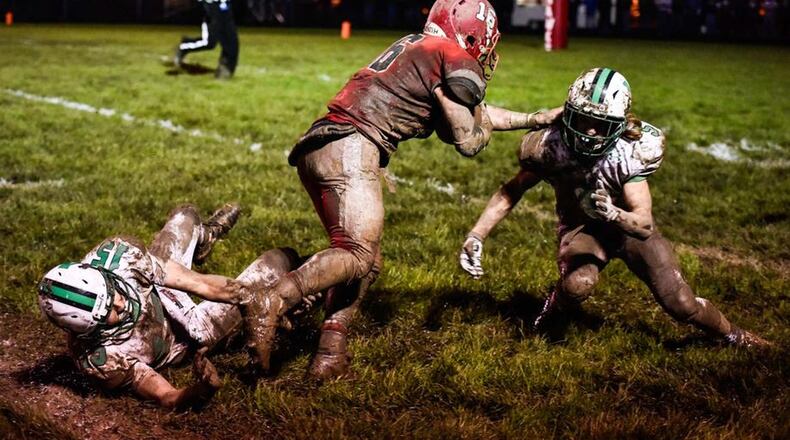 Madison’s Tyler Baumgartner (16) runs between Anna’s Griffin Doseck (15) and Caleb Kauffman (5) during last Friday’s Division V, Region 20 quarterfinal at Brandenburg Field in Madison Township. NICK GRAHAM/STAFF