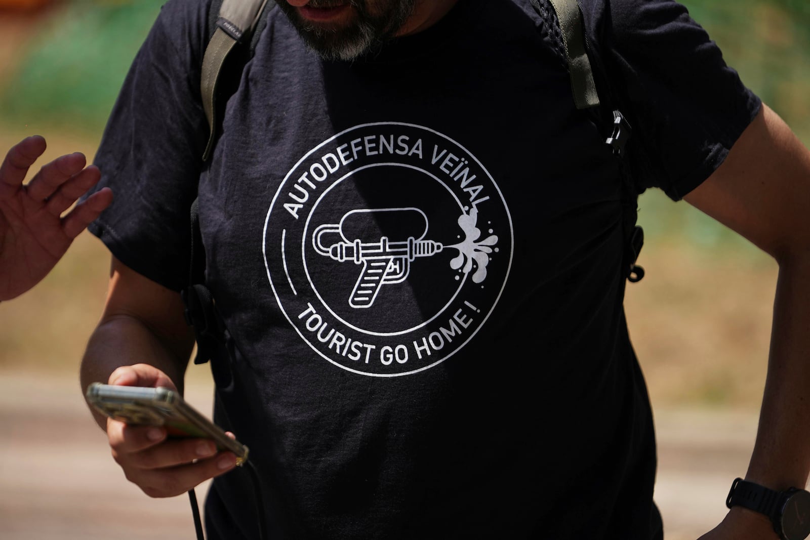 A person wears a t shirt with the message reading 'Neighborhood auto defense - Tourists go home' during a protest against overtourism in Barcelona, Spain, Sunday, June 15, 2025. (AP Photo/Pau Venteo)