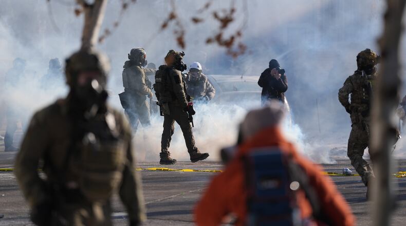 Federal immigration officers deploy tear gas at observers after a shooting Saturday, Jan. 24, 2026, in Minneapolis. (AP Photo/Abbie Parr)