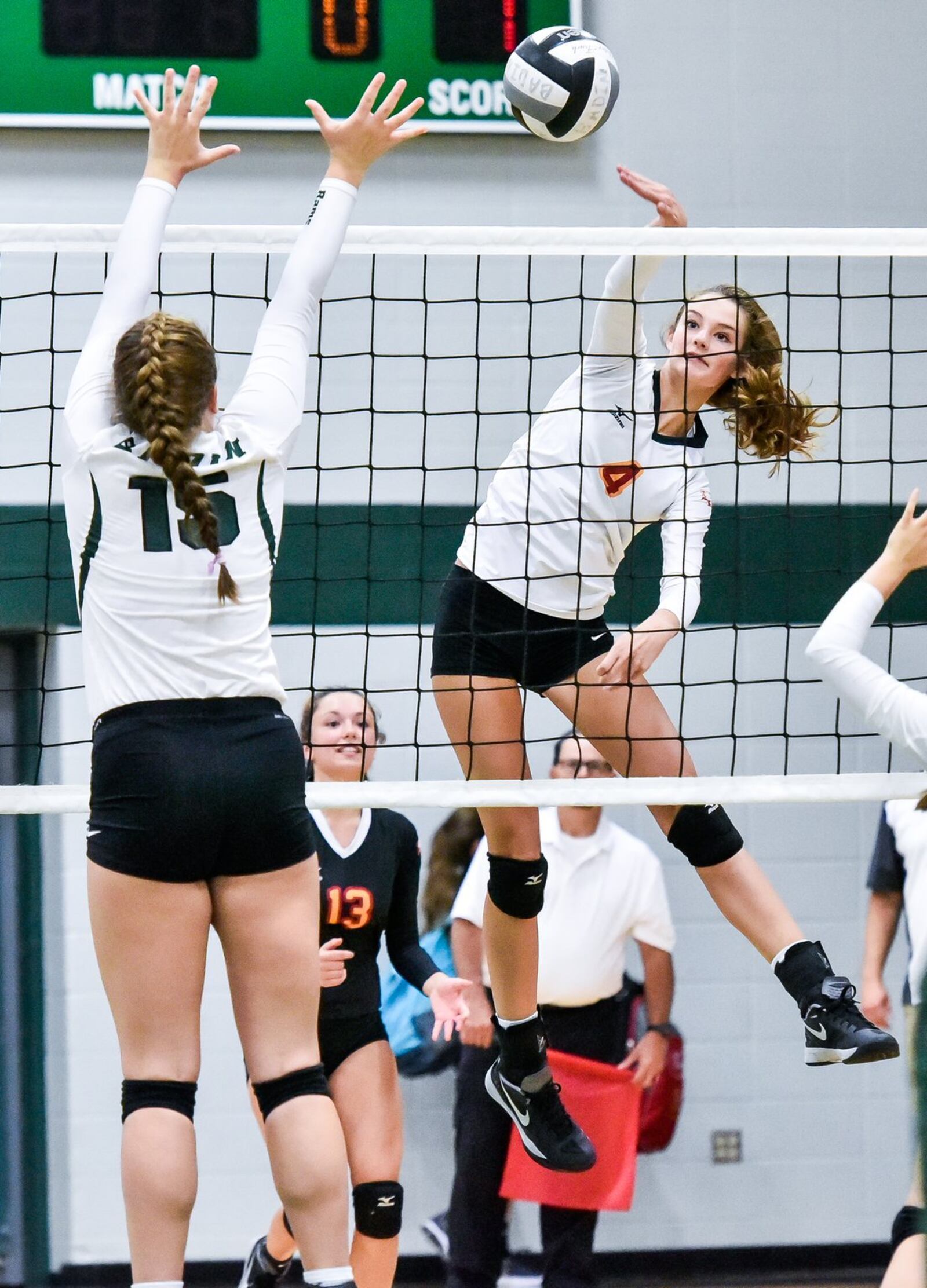 Fenwick’s Elizabeth Hoerlien (4) hits the ball as Badin’s Samantha Raley (15) attempts a block during their volleyball match Thursday night at Mulcahey Gym in Hamilton. NICK GRAHAM/STAFF
