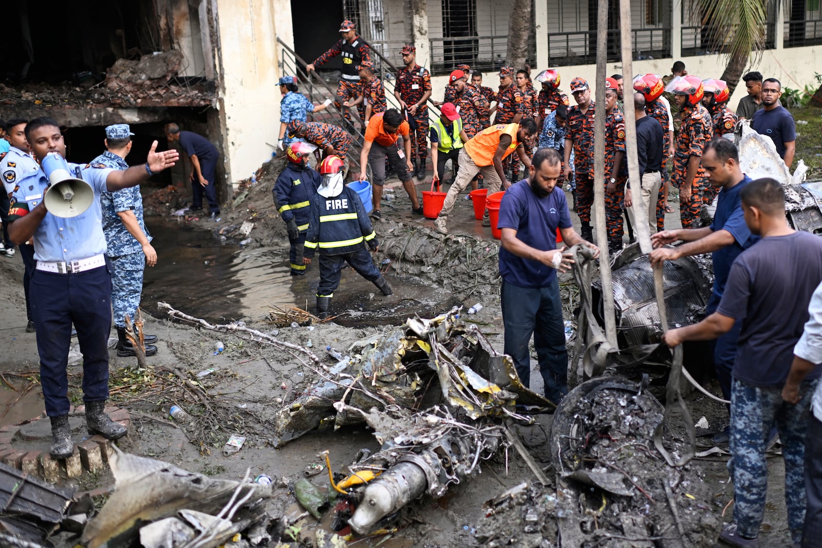Firemen work at the site of a Bangladesh Air Force training aircraft that crashed into a school campus shortly after takeoff in Dhaka, Bangladesh, Monday, July 21, 2025. (AP Photo/Mahmud Hossain Opu)