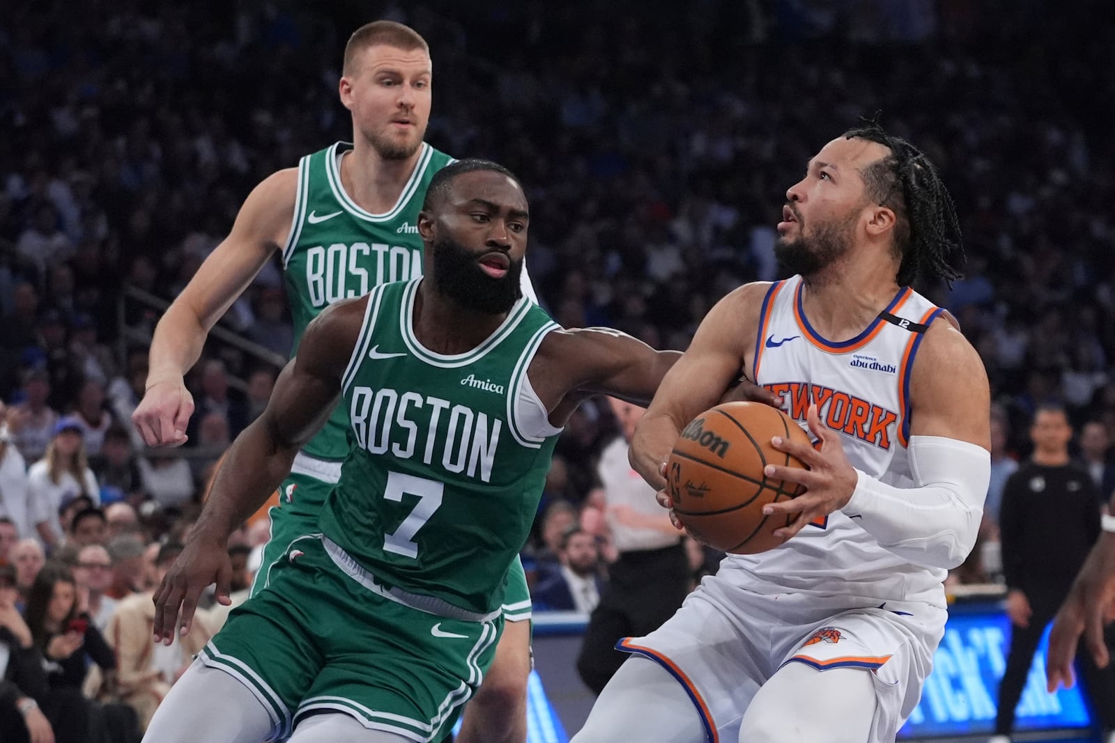 Boston Celtics' Jaylen Brown (7) defends New York Knicks' Jalen Brunson as Kristaps Porzingis watches during the first half of Game 6 in the Eastern Conference semifinals of the NBA basketball playoffs Friday, May 16, 2025, in New York. (AP Photo/Frank Franklin II)
