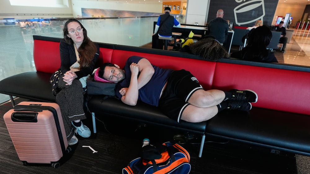 Jamie Sims left, and Carlos Serna, right, try to get some rest as they wait for their cancelled flight to El Paso, texas to be rescheduled at Love Field Airport in Dallas, Monday, March 16, 2026. (AP Photo/Tony Gutierrez)