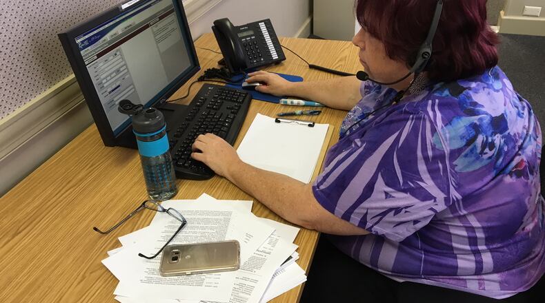 Catherine Myers, a Helplink 2-1-1 community outreach coordinator, answers phone calls this week in Dayton. BARRIE BARVER | STAFF