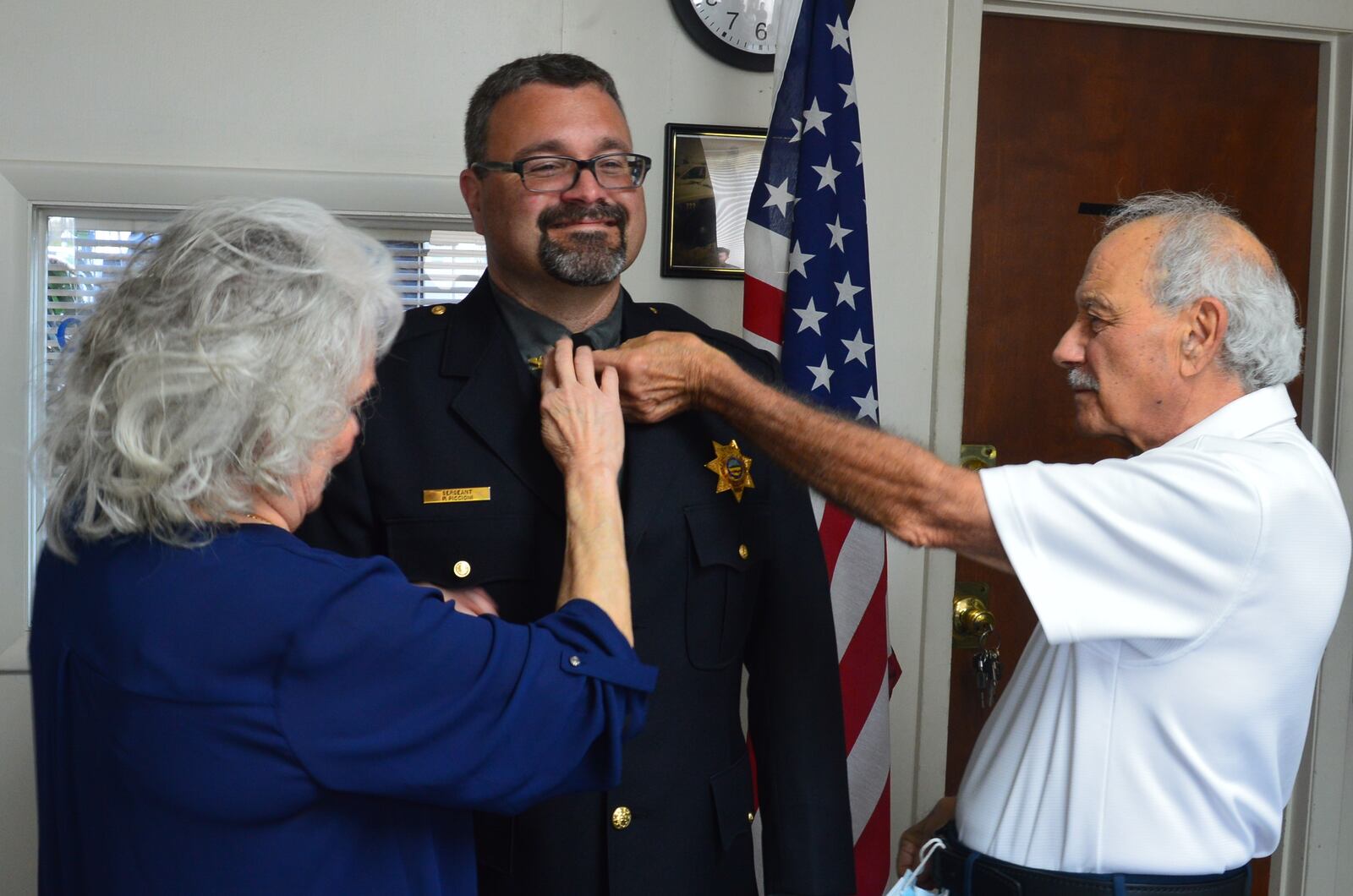 Suzanne and Patrick Piccioni place the eagle pins on the collar of their son, Patrick Piccioni, after he was sworn in as the new police chief of Oxford Township. CONTRIBUTED/BOB RATTERMAN