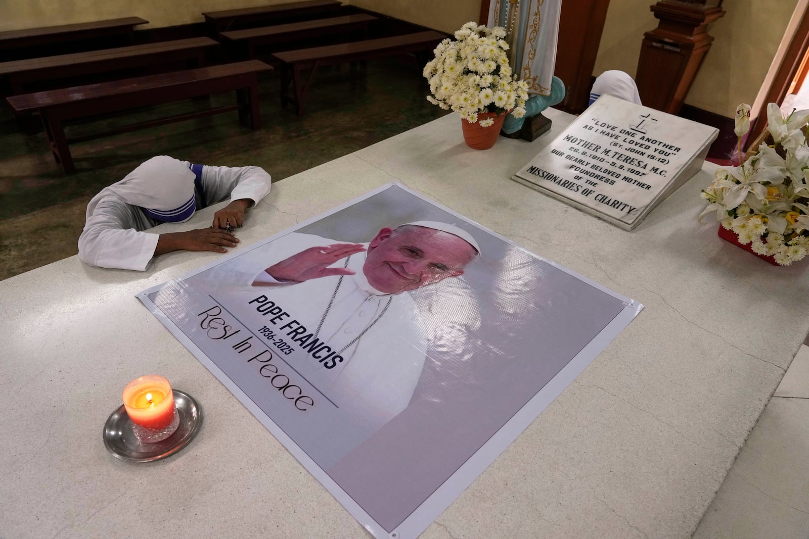 A Catholic nun of the Missionaries of Charity, the order founded by Saint Teresa, prays as a portrait of Pope Francis is placed over the tomb following his death, in Kolkata, India, Tuesday, April 22, 2025. (AP Photo/Bikas Das)