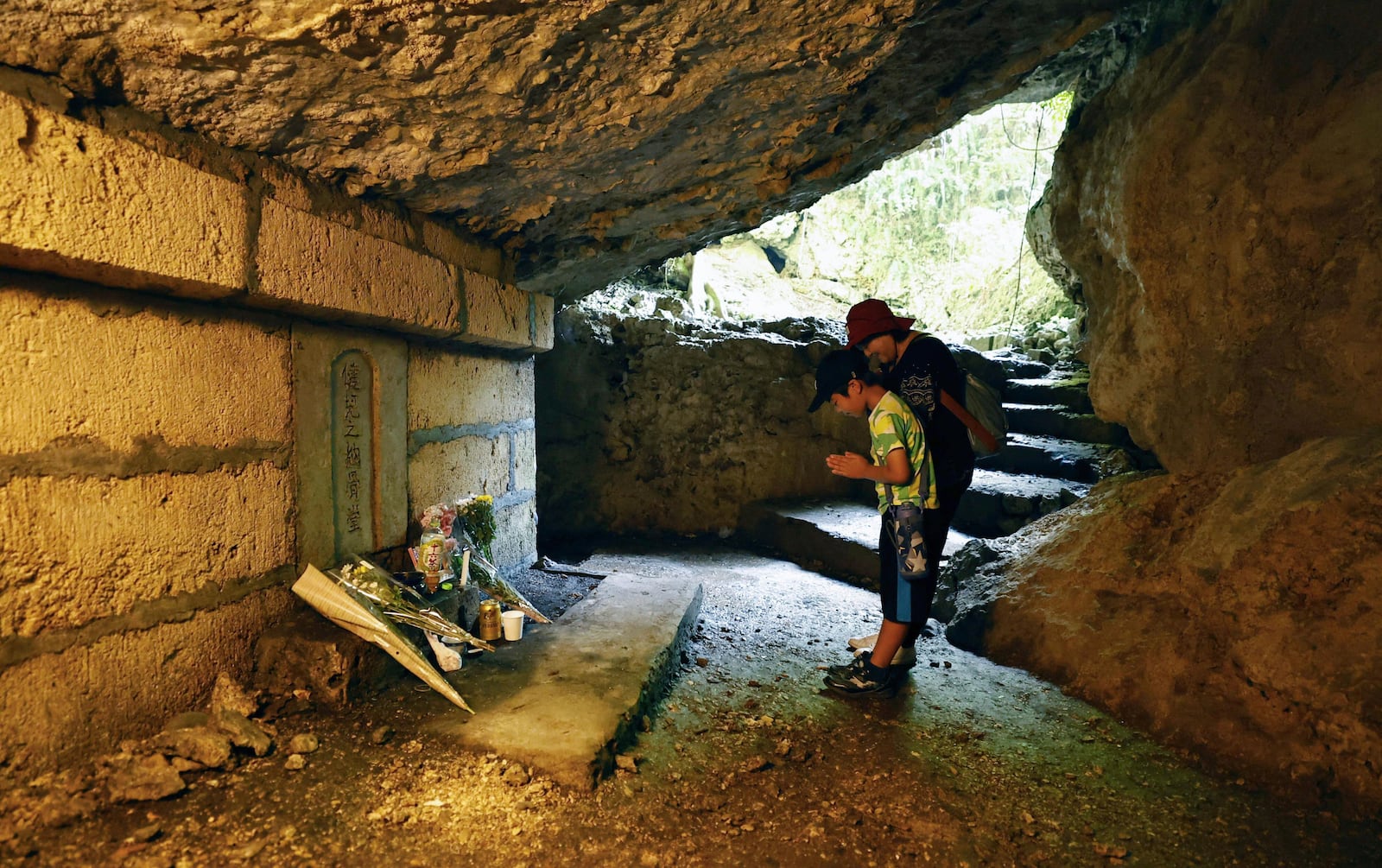 People pray for victims inside a cave in Itoman, Okinawa prefecture, southern Japan Monday, June 23, 2025 as Japan marked the 80th anniversary of the end of the Battle of Okinawa. (Mizuki Sakai/Kyodo News via AP)