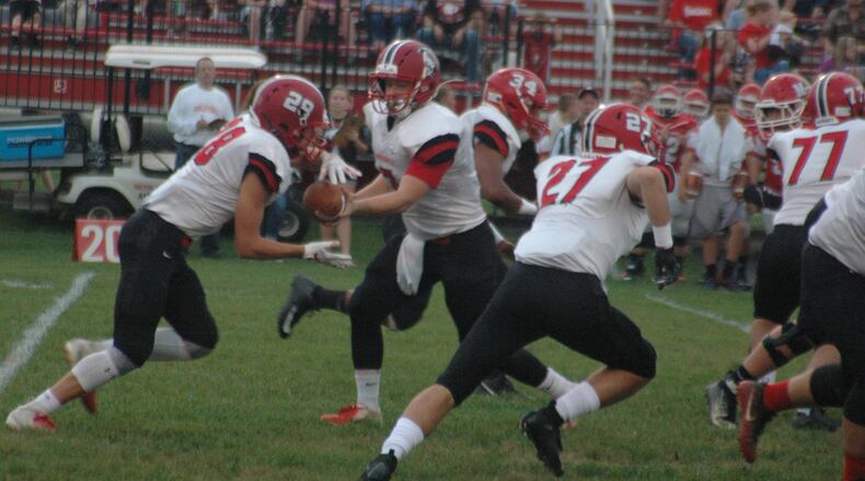 Madison’s Jake Phelps takes a handoff from quarterback Mason Whiteman as teammates Gabe Higgs (27) and Evan Crim (34) prepare to block during Friday night’s 34-0 win over Milton-Union at Memorial Stadium in West Milton. RICK CASSANO/STAFF