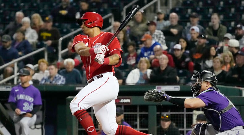 Cincinnati Reds' Christian Encarnacion-Strand, left, follows through on a swing on his infield single as Colorado Rockies catcher Brian Serven, right, looks on during the second inning of a spring training baseball game, Monday, March 6, 2023, in Goodyear, Ariz. (AP Photo/Ross D. Franklin)