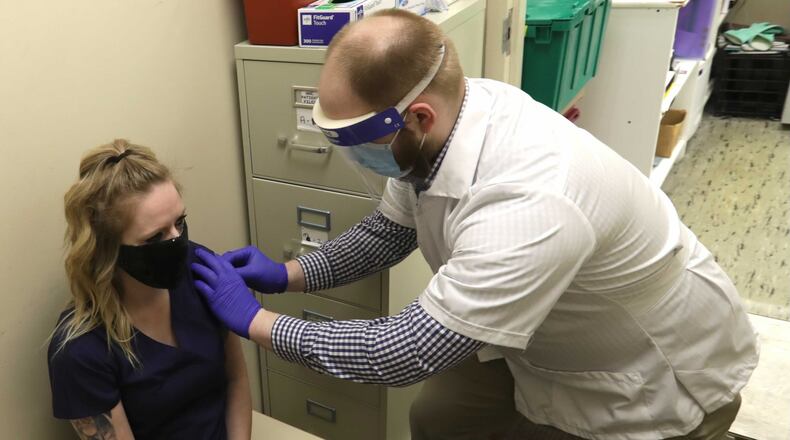 Andrew Hoffman, a pharmacist at Discount Drug Mart in Enon, gives Jennifer Boswell a flu shot at the pharmacy. BILL LACKEY/STAFF