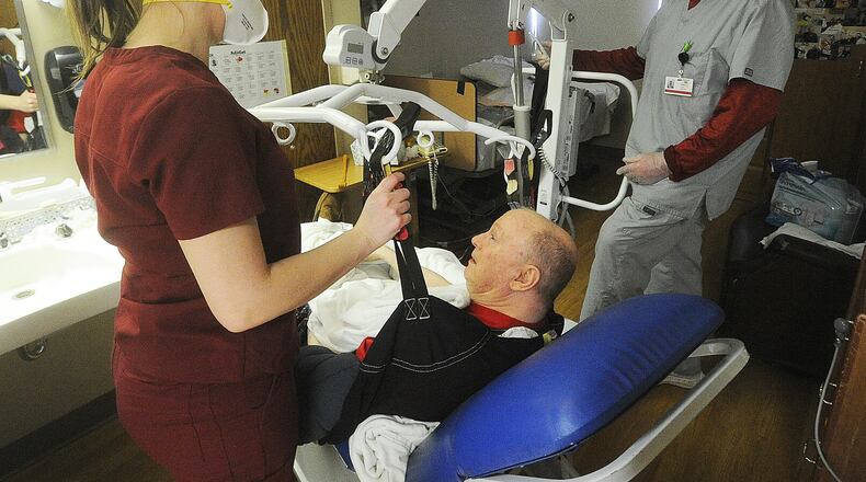 Staff members Sabrina Hall, STNA, left, and Kent Little, STNA, at the Friends Care Community Facility in Yellow Springs assist resident Woody Wilson, Monday Feb. 19, 2024. The Friends Care Community facility was ranked the highest for resident satisfaction in Greene County following a recent survey conducted by the state. MARSHALL GORBY\STAFF