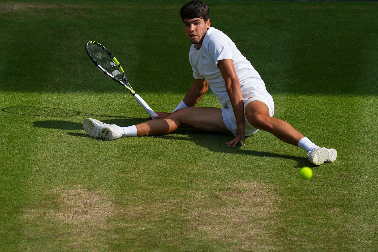 Carlos Alcaraz of Spain slips as he returns a shot by Italy's Jannik Sinner in the men's singles final at the Wimbledon Tennis Championships in London, Sunday, July 13, 2025. (AP Photo/Joanna Chan)