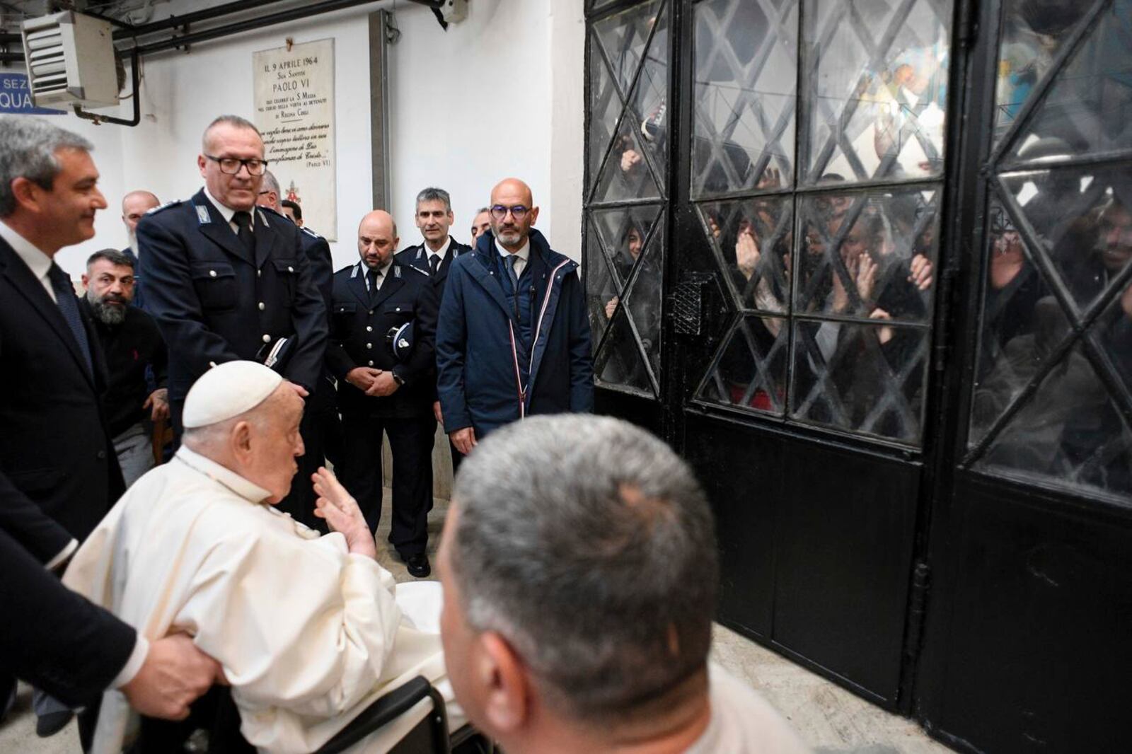 Pope Francis waves at inmates behind a closed gate during his visit to the Regina Coeli penitentiary in Rome on Holy Thursday, Thursday, April 17, 2025. (Holy See Press Office via AP, HO)