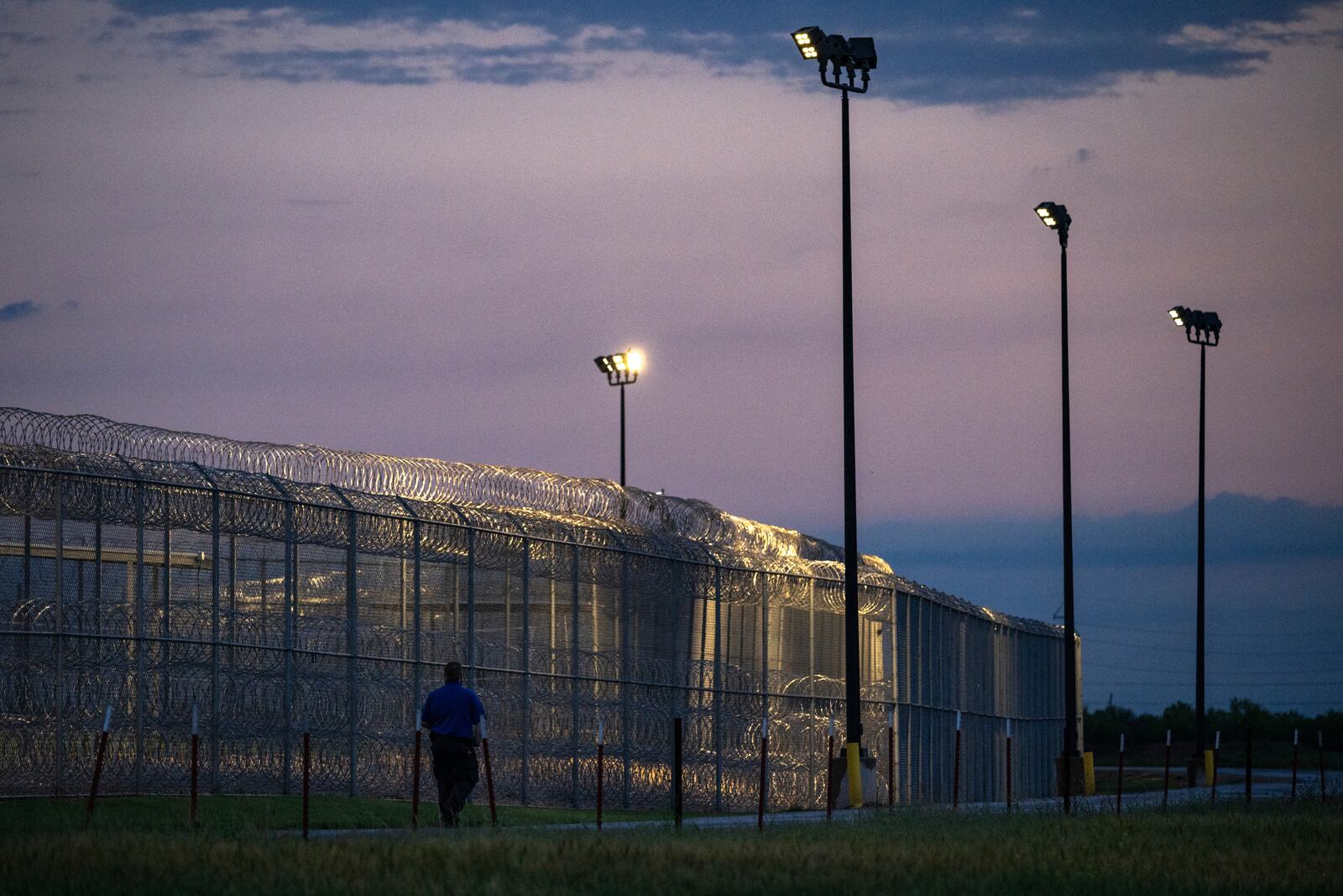 A Management & Training Corporation employee patrols the exterior of the Bluebonnet Detention Center Thursday, April 24, 2025, in Anson, Texas (AP Photo/Eli Hartman)