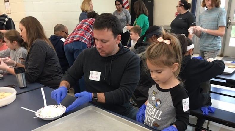 Ella Wilkerson and father, Brian, decorate cookies to be included in Thanksgiving meals as part of Companion Cuisine at Monroe High School cafeteria on Thursday. LAUREN PACK/STAFF