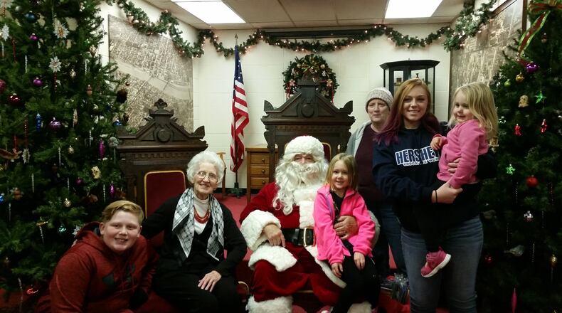 Santa Claus sits next to Ann Dennett, longtime chairwoman of the German Village Christmas Walk. They are pictured with Dennett’s daughter Debbie, and Dennett’s four great grandchildren, Kylie, Lucas, Charlotte and Clara. CONTRIBUTED