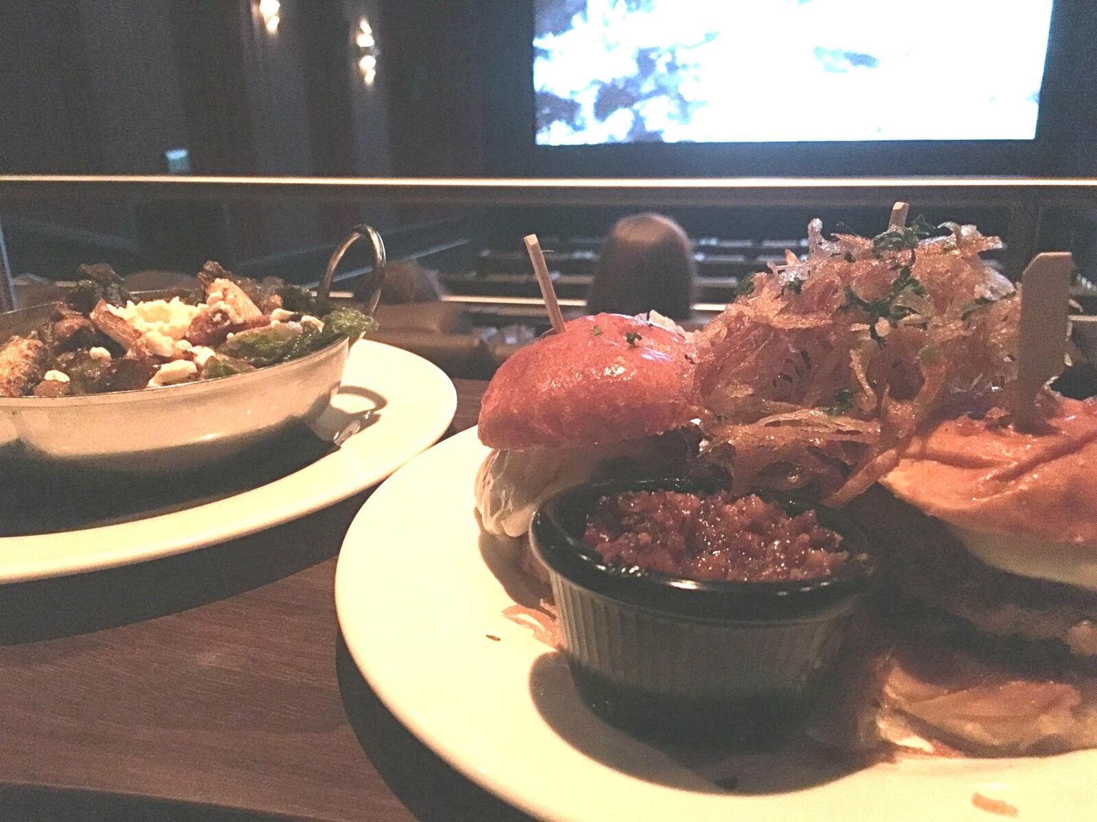 The seared Wagyu beef sliders ($14) on buttered brioche rolls with sweet tomato jam and melted butterkäse German cheese served with a pile of onion straws and the crispy brussel sprouts ($9) with caramelized onion and feta make for a winning combination. CONTRIBUTED PHOTO BY ALEXIS LARSEN